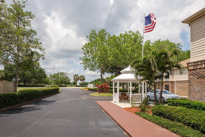 A small gazebo next to a road with an American flag and trees under an overcast sky.