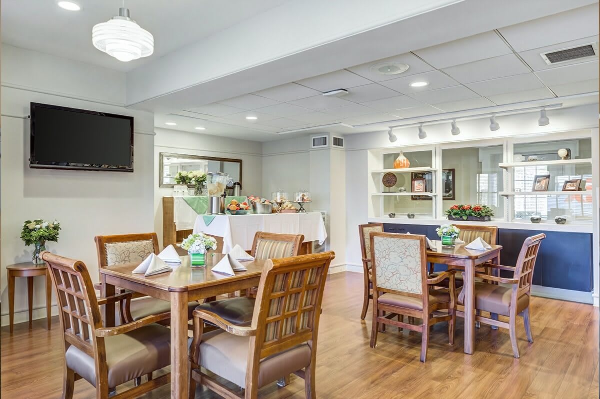 A cozy dining room with neatly arranged tables and chairs, featuring wooden flooring and stylish decor.
