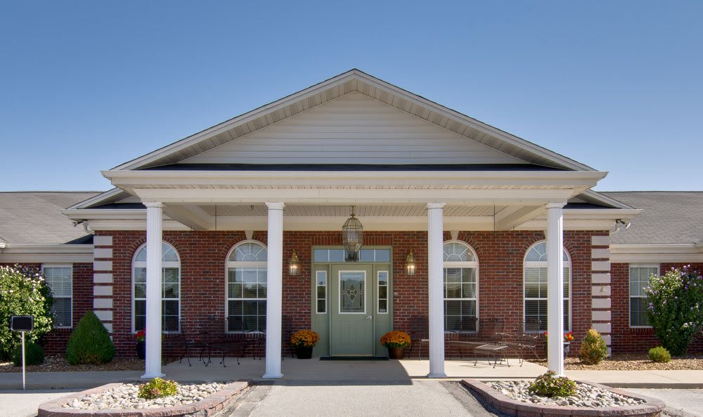 Front entrance of a brick building with columns and a green door.