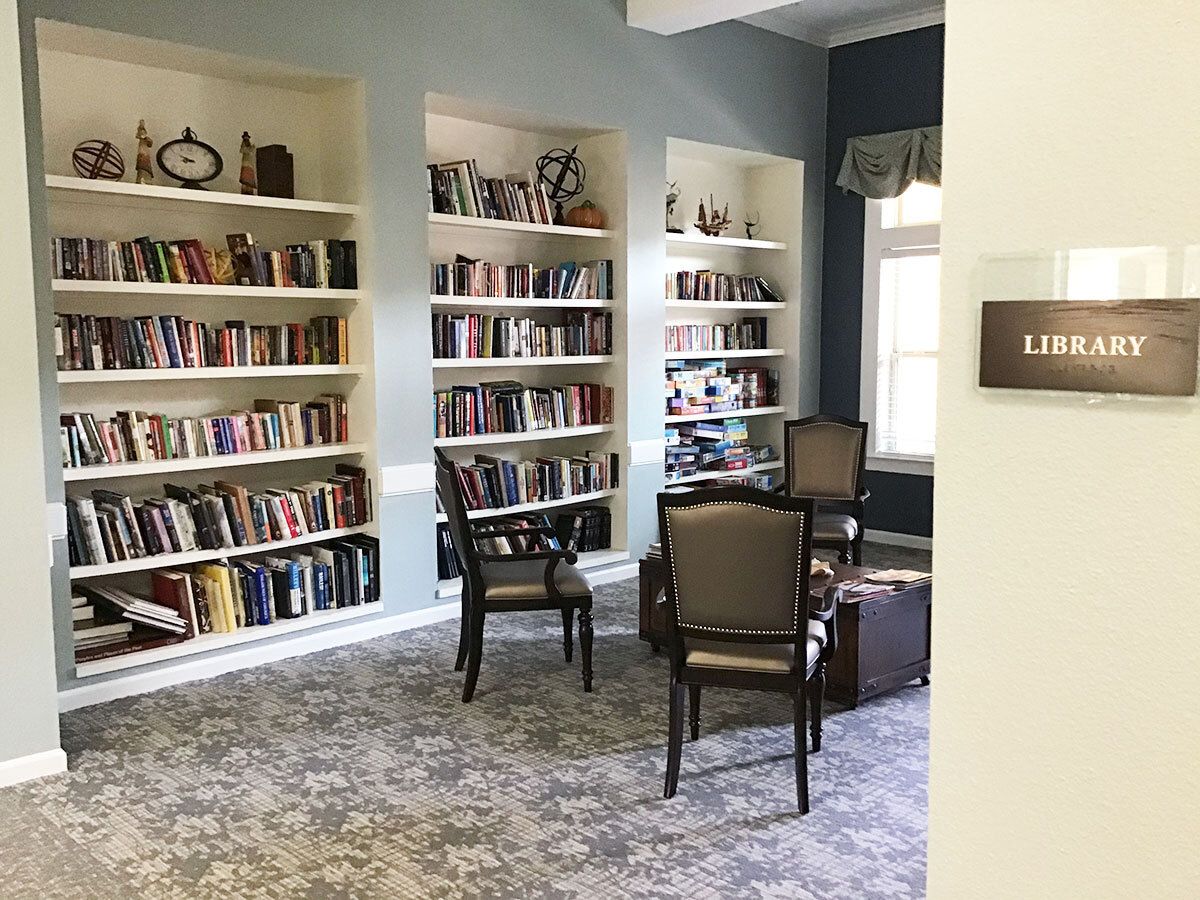 A cozy library corner with bookshelves, chairs, and a reading area.