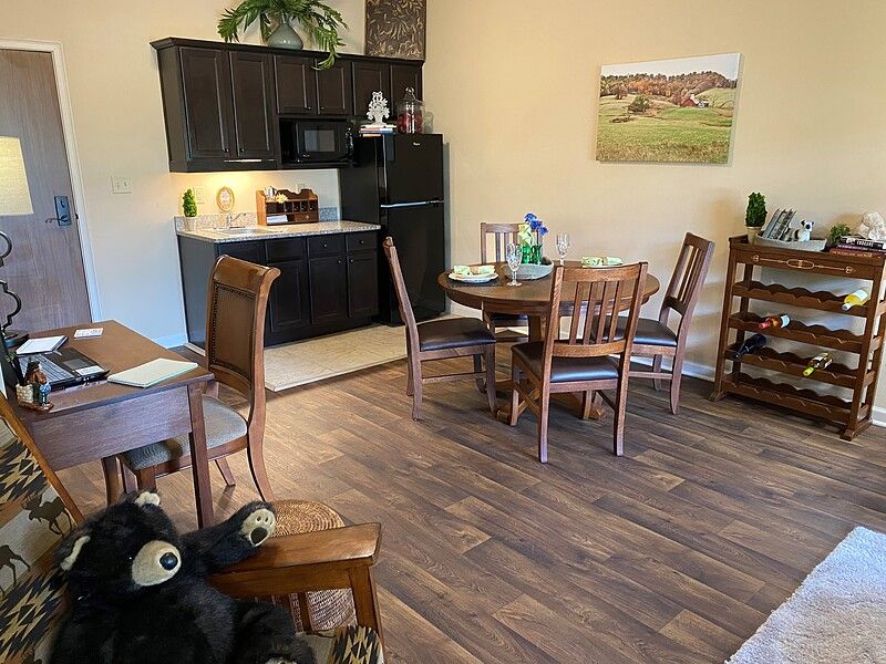 A cozy kitchen and dining area with wooden flooring, featuring a table, chairs, and modern appliances.