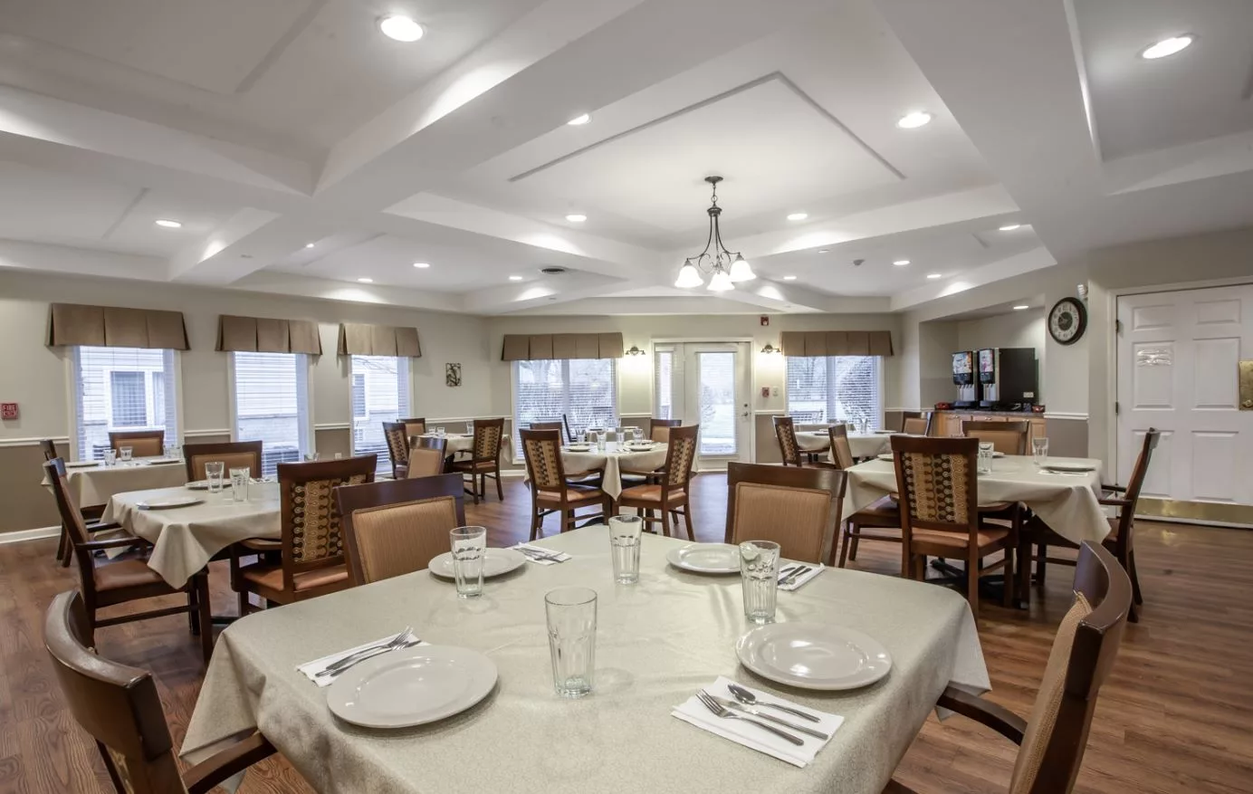 A spacious and well-lit dining room with neatly arranged tables and chairs, ready for guests.