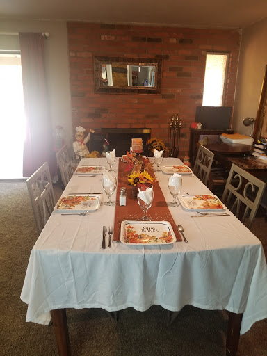 A beautifully set dining table ready for a meal, featuring a white tablecloth and a rustic wooden centerpiece.