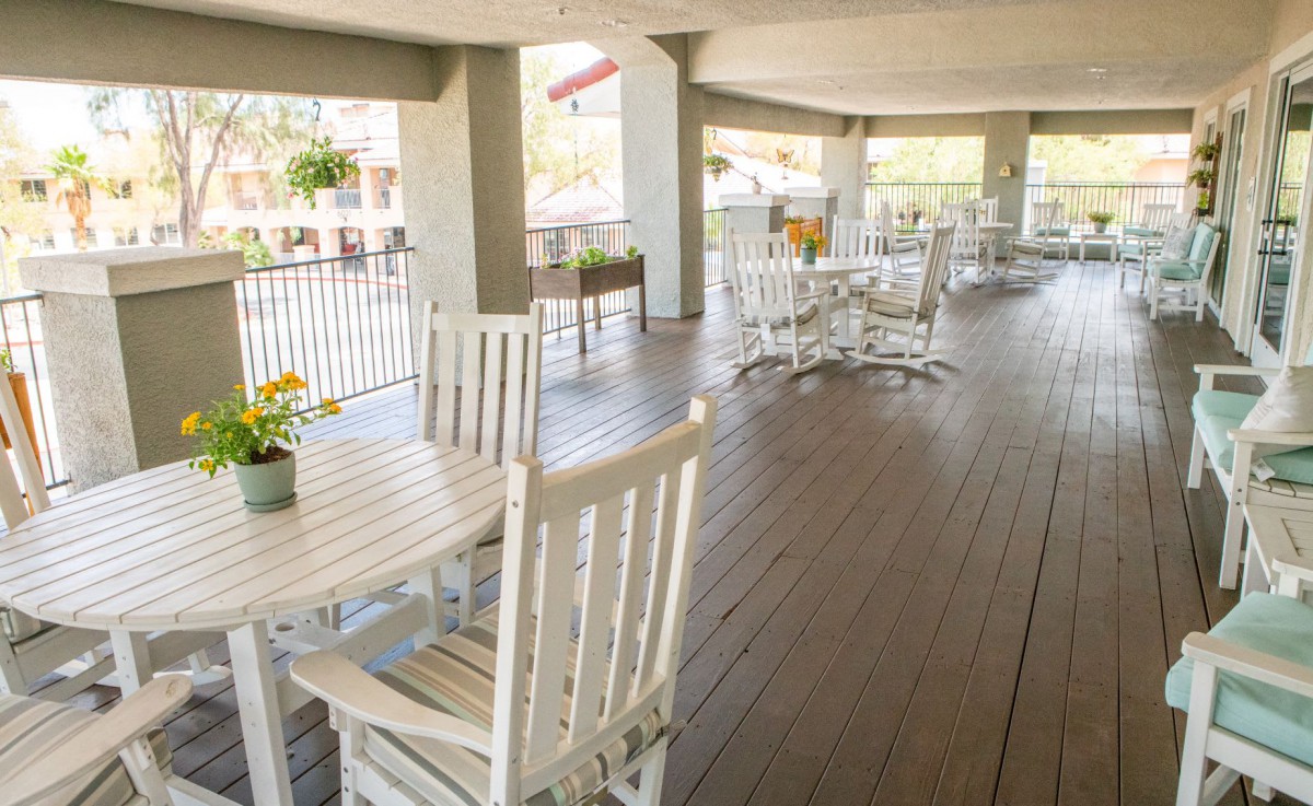 A spacious patio with wooden tables and chairs, enhanced by potted plants.
