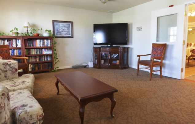 A cozy living room with a television, coffee table, and bookshelf.