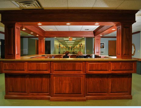 A wooden reception desk in a well-lit office lobby.