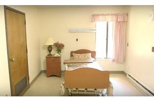 A simple bedroom with a single bed, nightstand, and window.