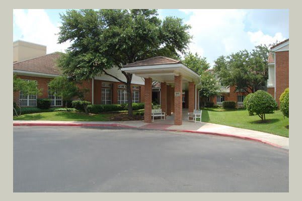 A building entrance with a covered walkway and surrounding greenery.