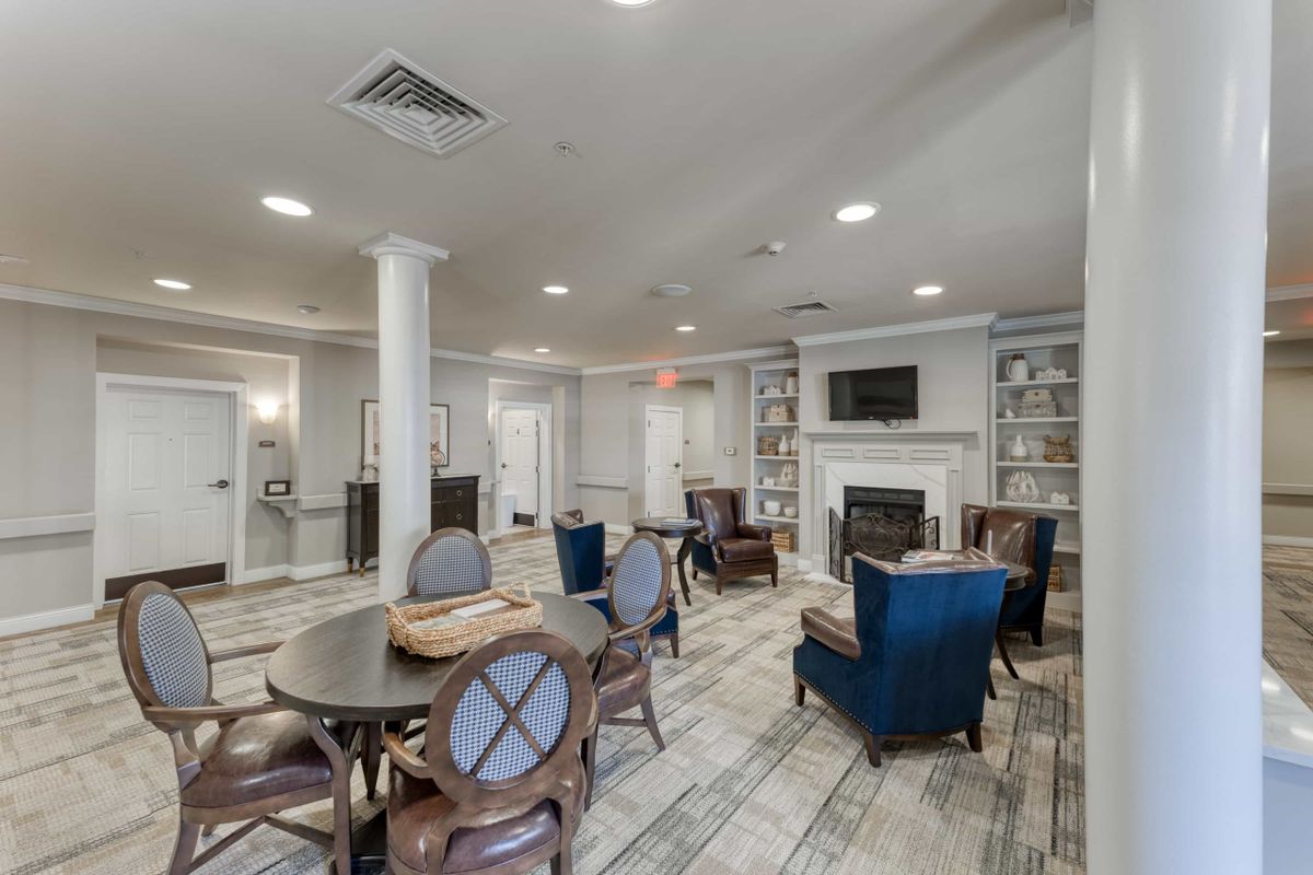 A cozy lounge area featuring tables, chairs, a fireplace, and built-in bookcases.