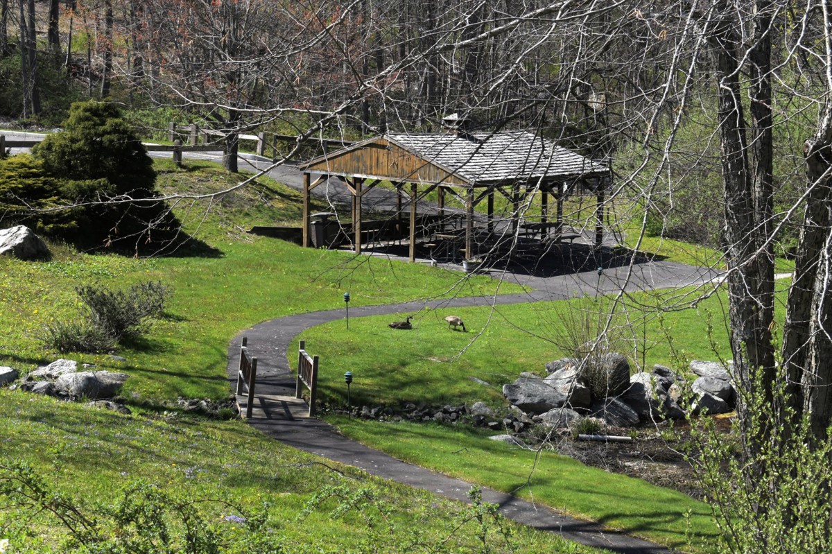 A serene park scene featuring a gazebo, a winding pathway, and lush greenery.