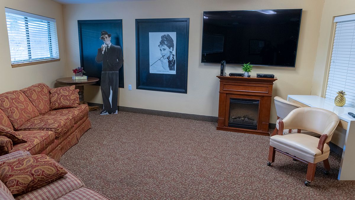 A cozy living room with a television, fireplace, artwork on the wall, and a cardboard cutout.