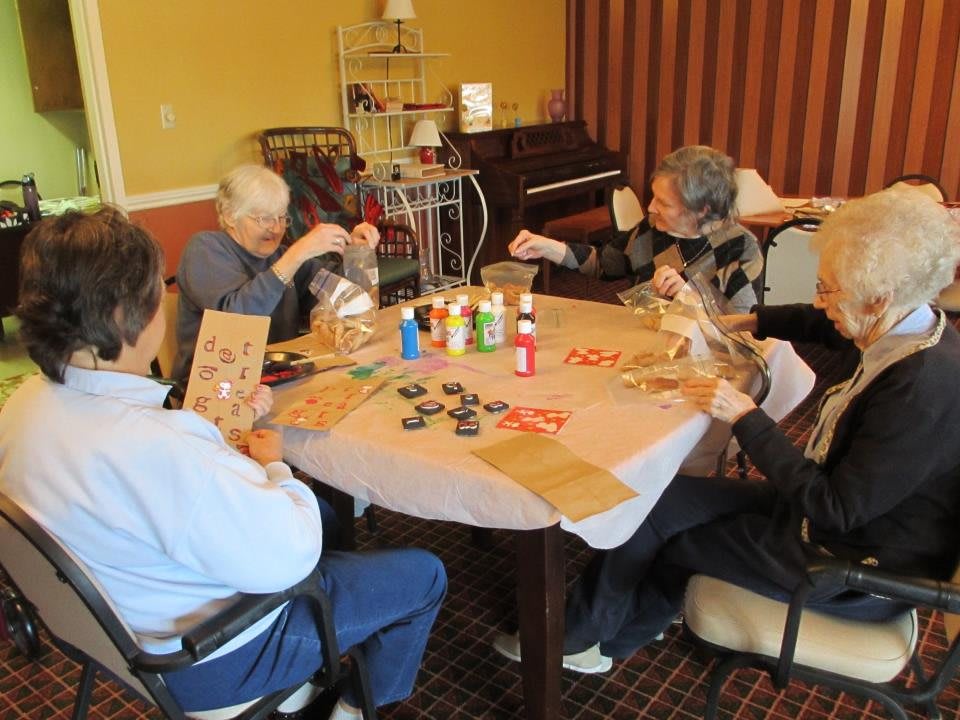 A group of elderly individuals engaging in arts and crafts at a table indoors.