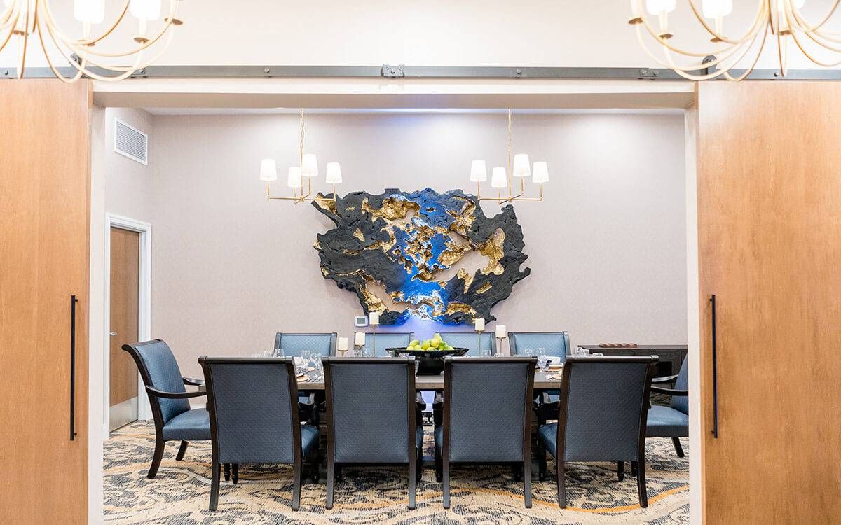 A modern conference room featuring a long table, upholstered chairs, and contemporary wall art.