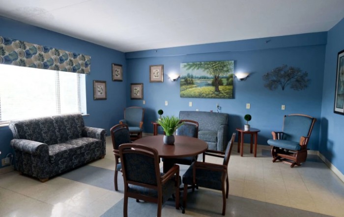 A cozy living room with blue walls, featuring a table and chairs, couch, and decorative artwork.
