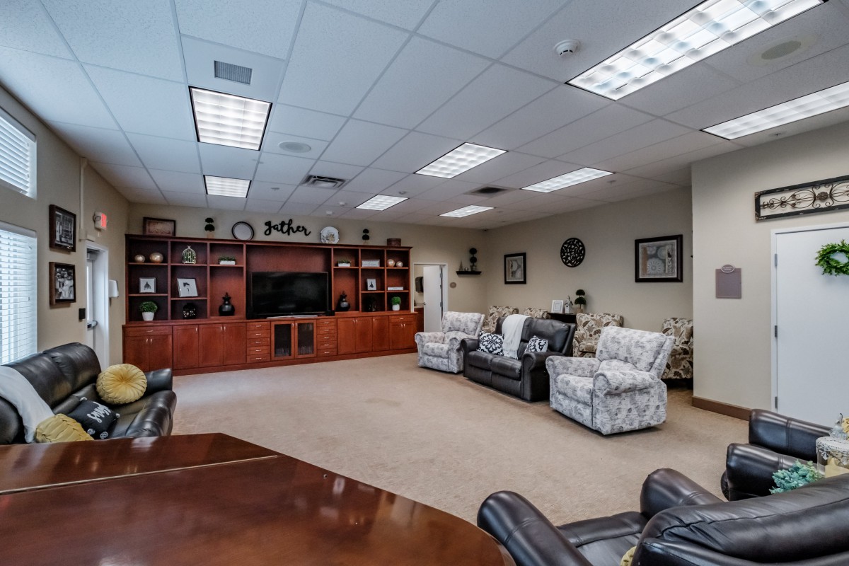 A spacious conference room featuring comfortable seating, a large shelving unit, and ample lighting.