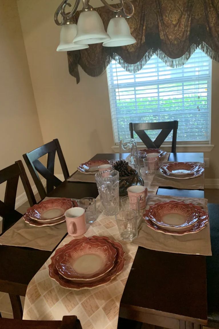 A dining table set for a meal with plates, glasses, and placemats.