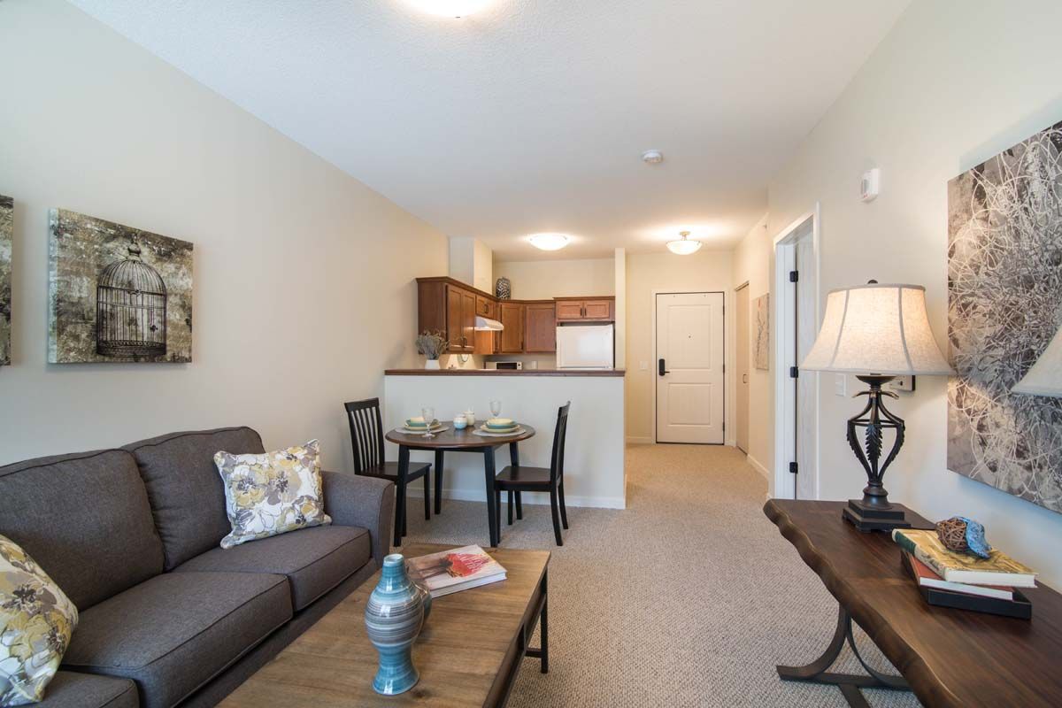 A cozy living space with a sofa, dining table, and a view into a kitchenette.