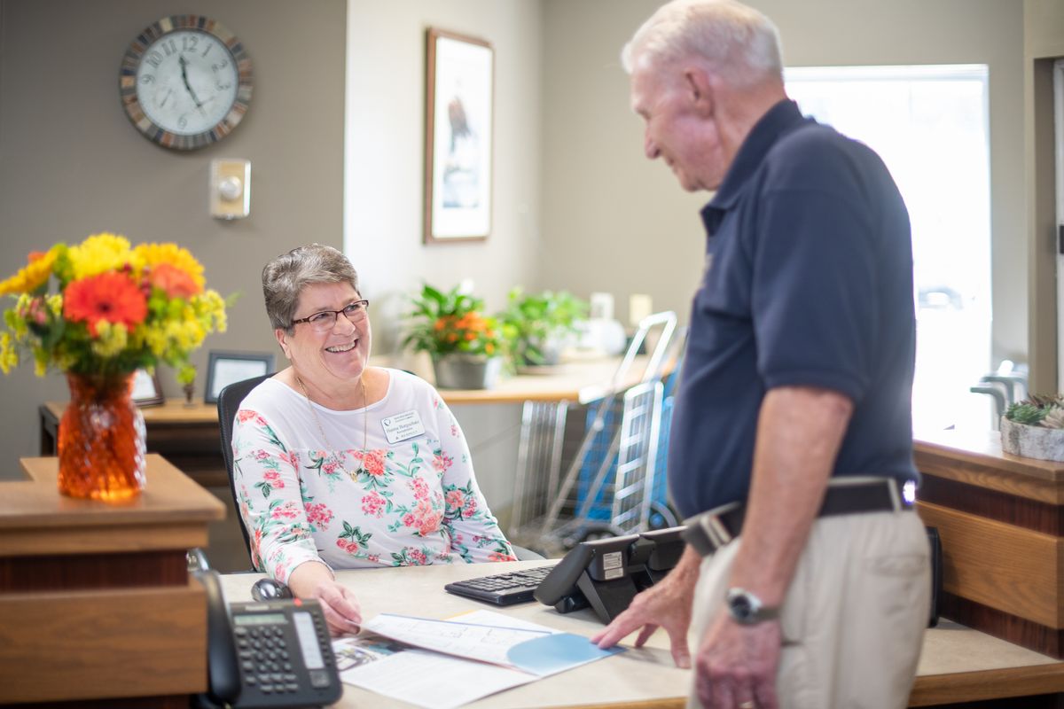 Two people engaged in a friendly conversation at an office desk.
