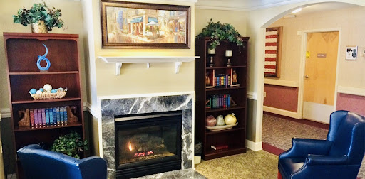 A cozy living room setup featuring a marble fireplace, a bookshelf filled with books, and a piece of artwork above the mantel.