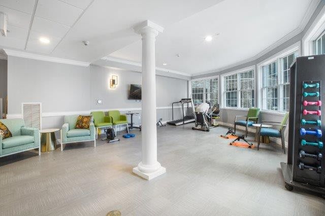 A bright and modern gym room with exercise equipment and seating.