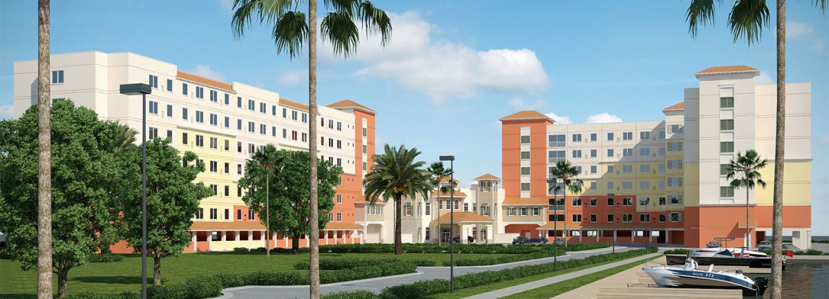 A view of a modern building complex with palm trees and lush greenery.