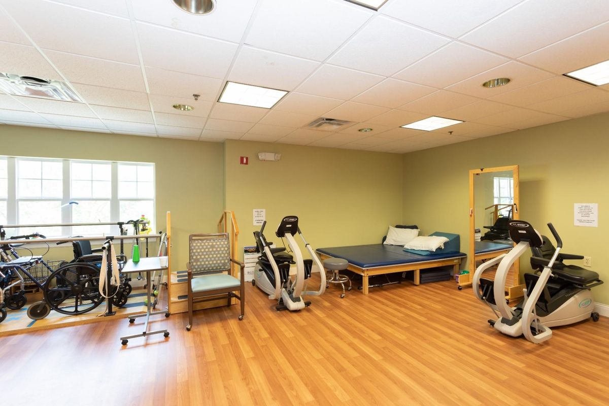 A spacious physical therapy room equipped with exercise machines and therapy beds.