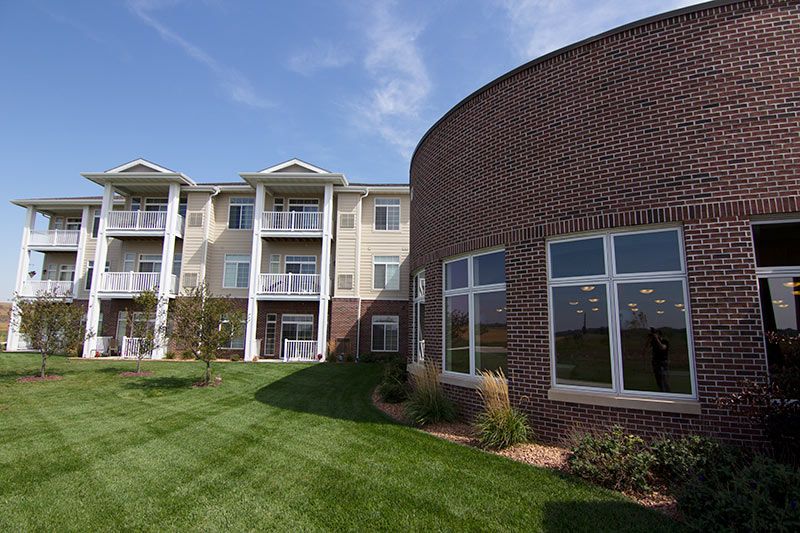 A modern apartment complex with a well-maintained lawn and brick exterior.