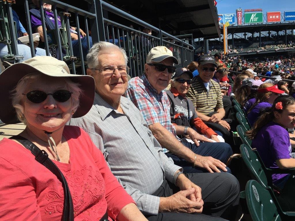 A group of people sitting in a stadium enjoying a sunny day.