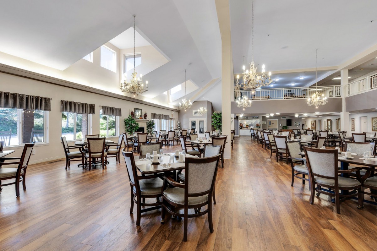 A spacious and elegantly designed dining area with chandeliers and neatly arranged tables.