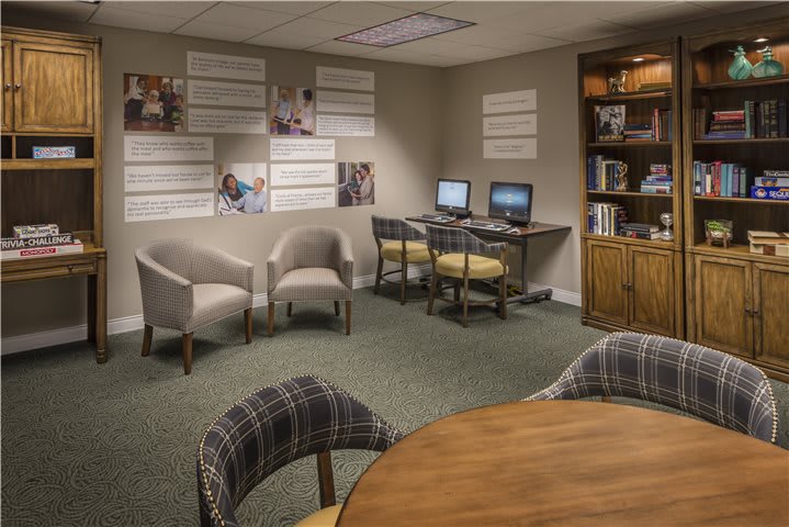 A cozy office space with computers, chairs, and a bookshelf.