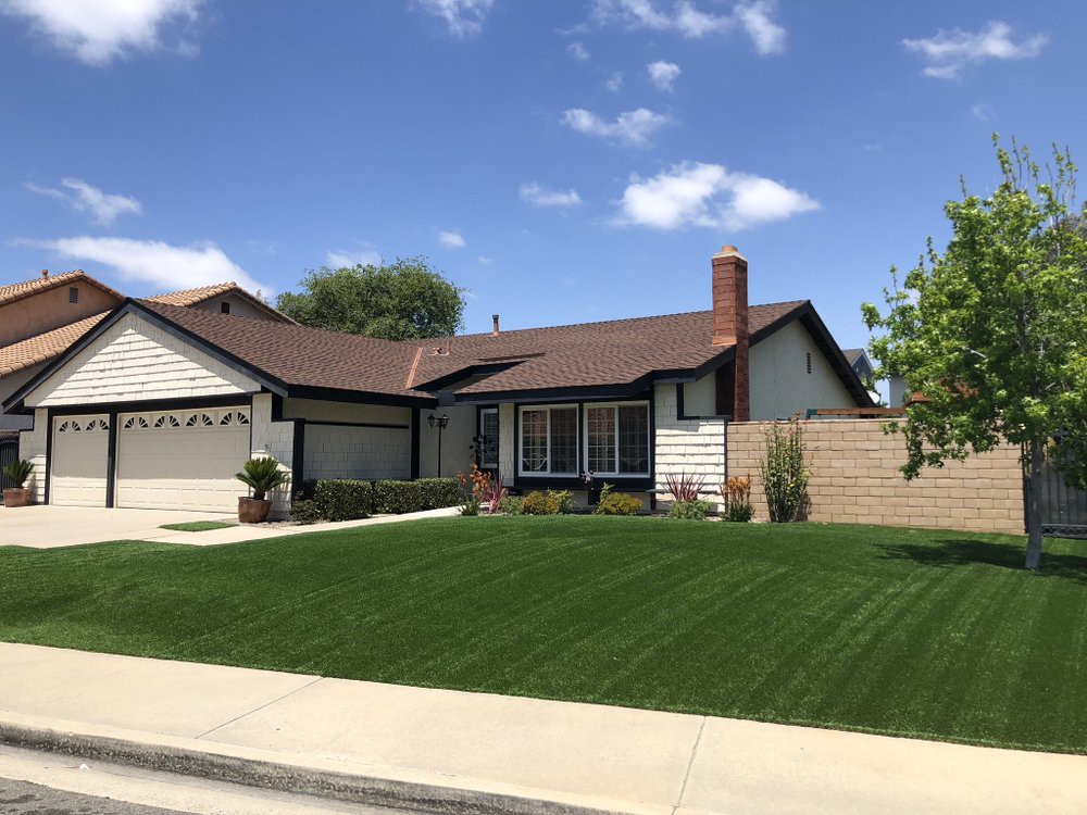 A suburban house with a well-manicured lawn under a clear blue sky.