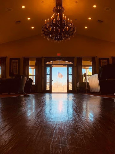 A warm and inviting lobby space with elegant lighting, showcasing a wooden floor and large doors that let in natural light.