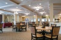 A spacious dining room with neatly arranged tables and chairs, well-lit by ceiling lights.
