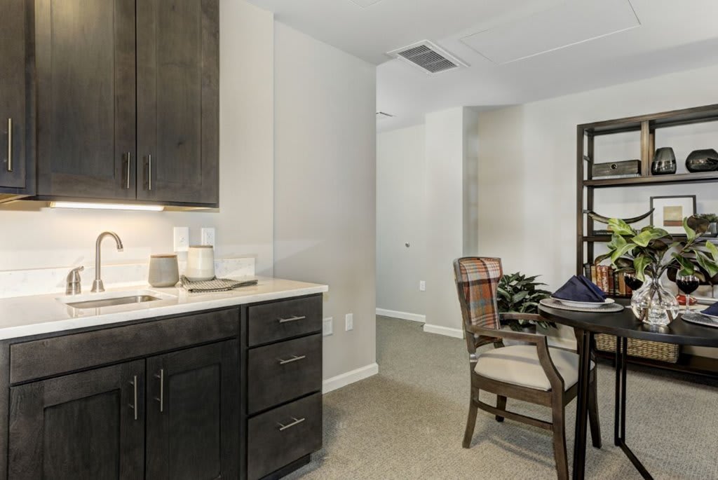 A modern kitchen and dining area featuring dark cabinets and elegant furniture.
