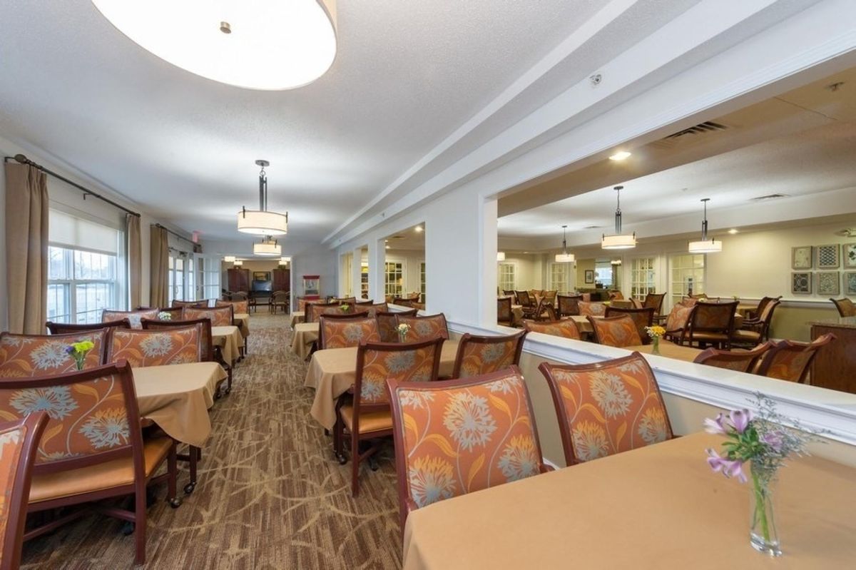 A spacious dining area with neatly arranged tables and chairs, featuring elegant lighting and decor.