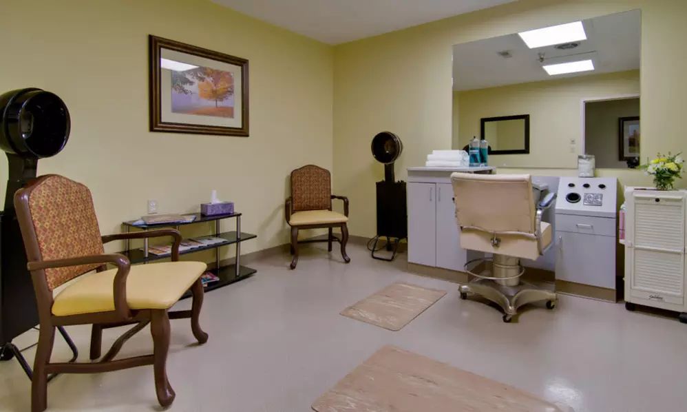 A cozy salon interior with chairs, a mirror, and hair styling equipment.