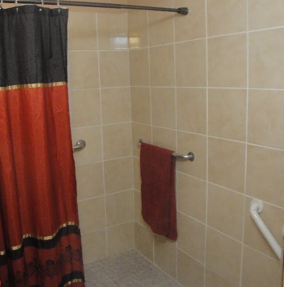 A tiled shower area with a colorful curtain and towel.