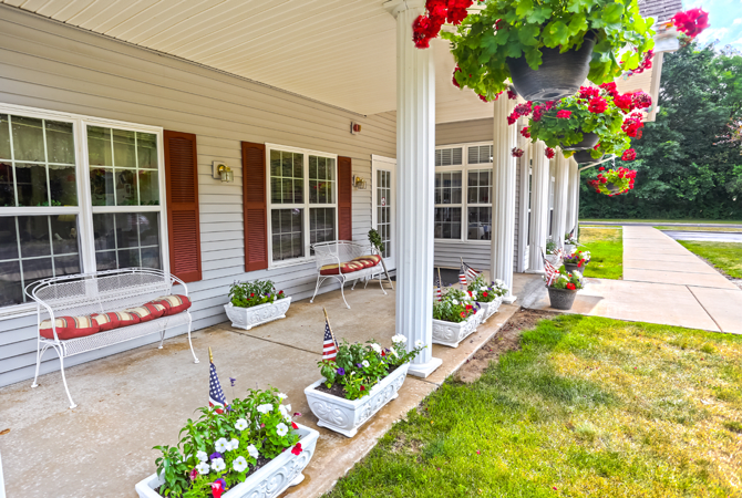 A welcoming porch with columns, adorned with flowers and hanging plants.