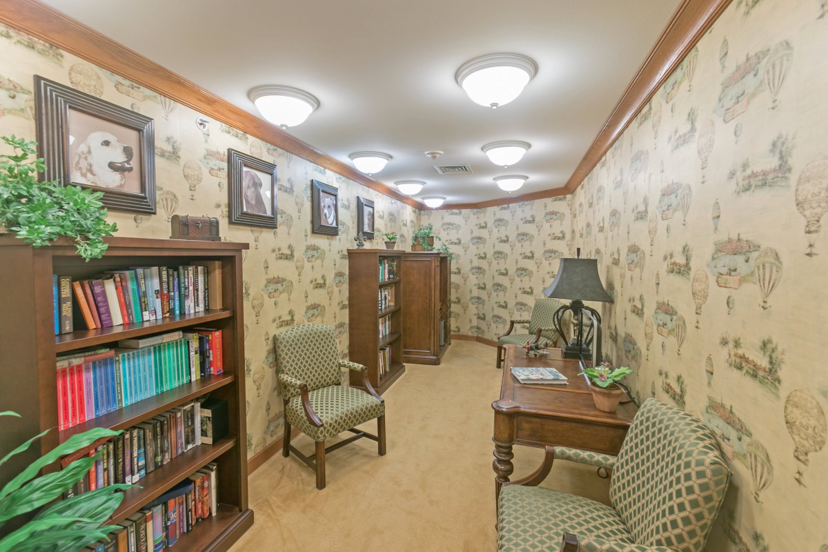 A cozy reading room with bookshelves, armchairs, and a writing desk.