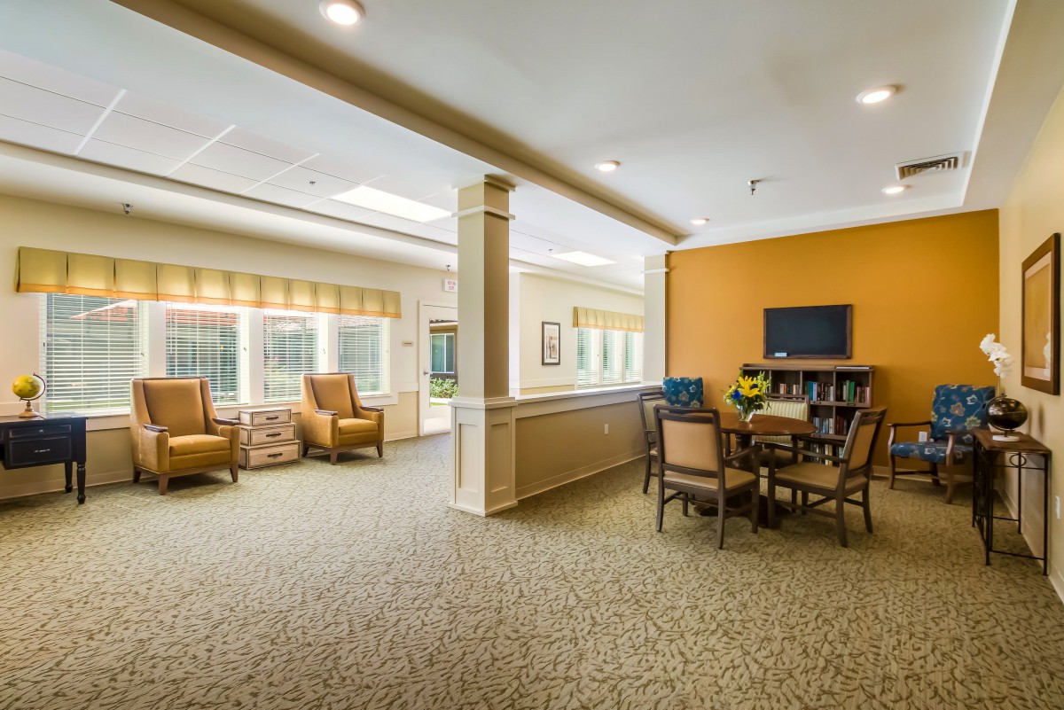 A cozy living space with comfortable seating, a table with chairs, and ample natural light through large windows.