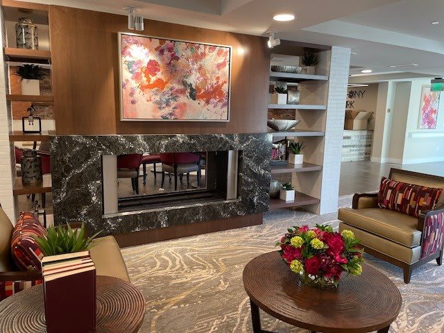 A modern living room with a fireplace, abstract artwork, and neatly arranged shelves.