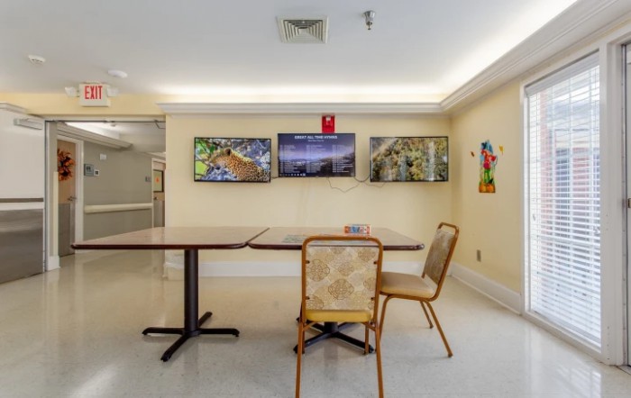 A simple room interior with a table, chairs, and artwork displayed on the wall.