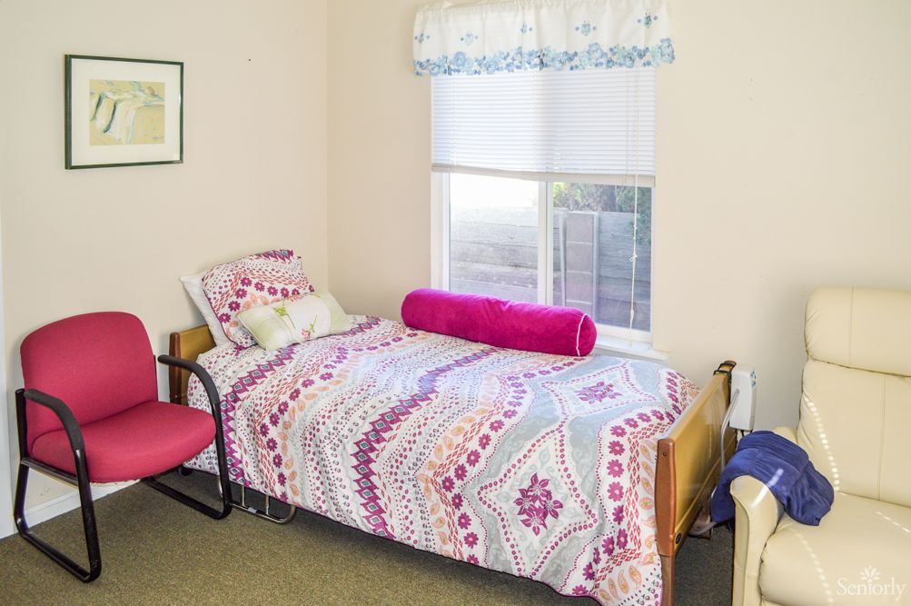 A cozy bedroom with a patterned bedspread and a window letting in natural light.