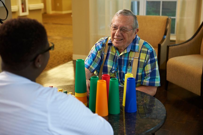 Two people engaged in a conversation while playing with colorful cups indoors.