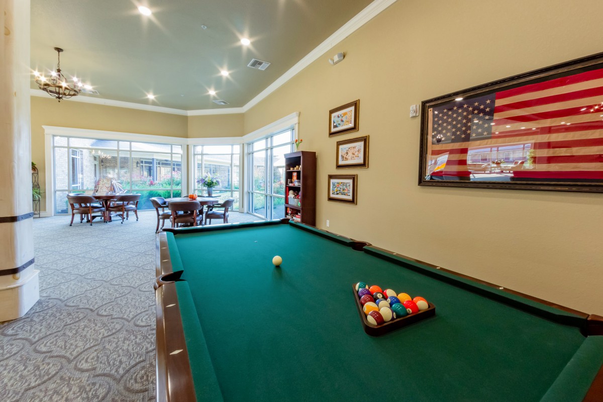 A well-lit game room featuring a billiard table ready for play.