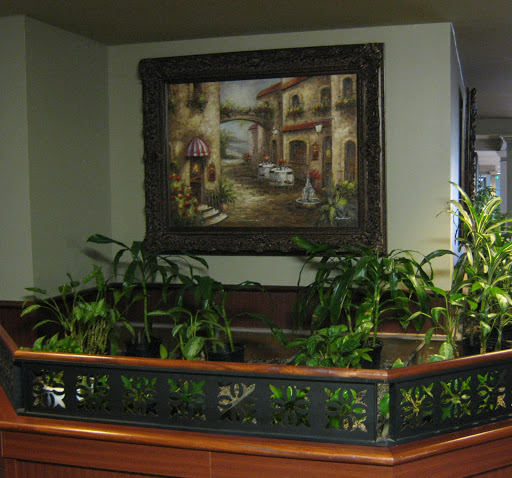 A cozy corner featuring a lush arrangement of plants beneath a decorative painting.