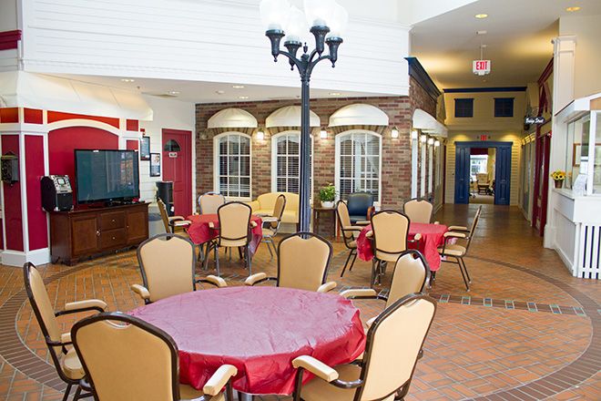 A cozy indoor dining area with round tables, comfortable chairs, and a brick wall backdrop.