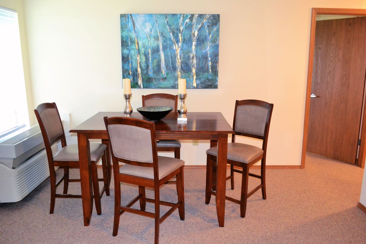 A dining room with a wooden table and chairs, complemented by wall art.