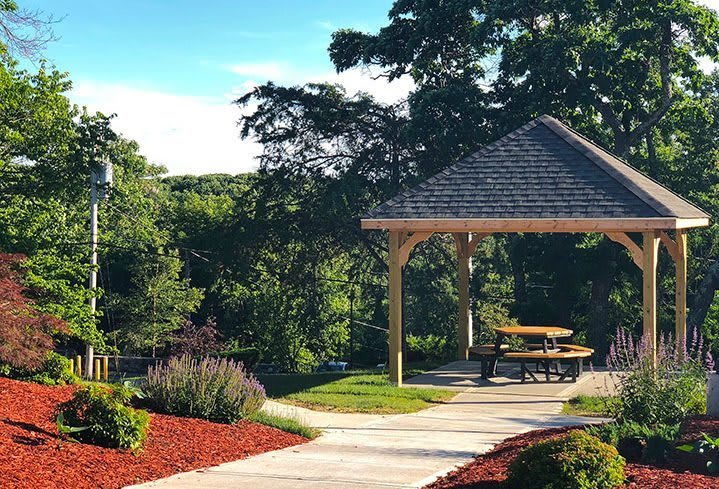 A serene outdoor picnic area with a gazebo surrounded by lush greenery.