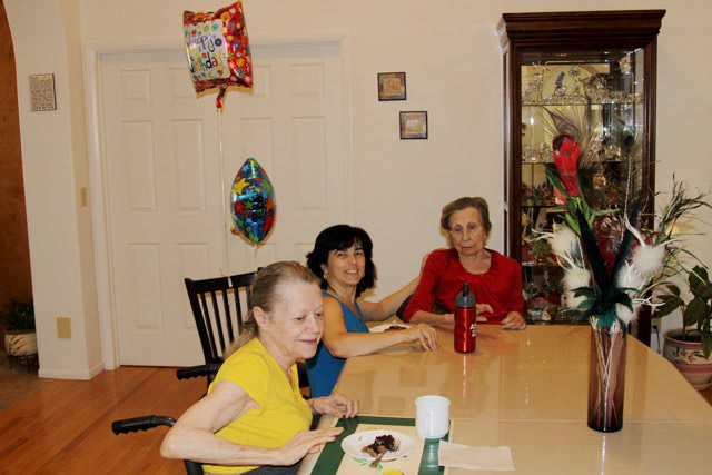 Three women sitting around a dining table during a celebration.